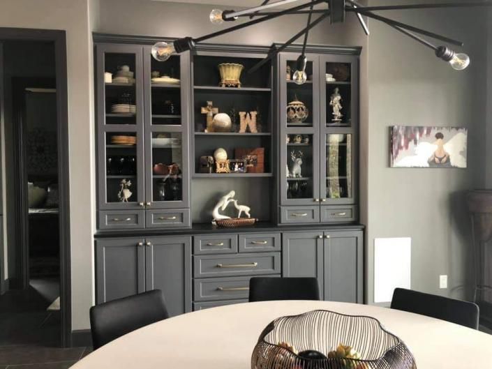 Dark gray dining room with built-in cabinets, decorative shelves, and a round table in the foreground
