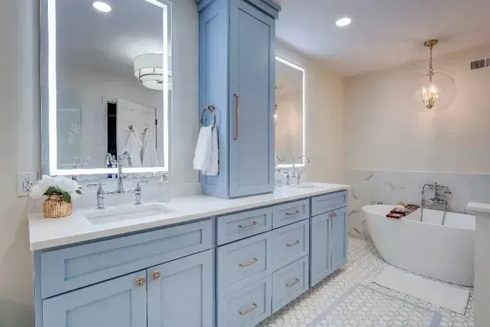 Bright bathroom with light blue vanity, large mirror, and freestanding tub by a window.