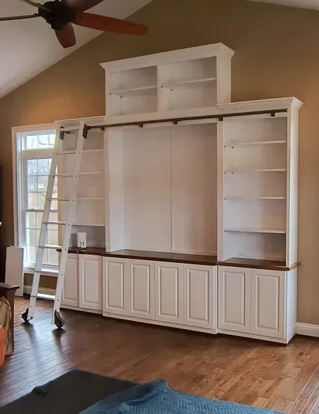 White built-in entertainment center with cabinets and shelves in a living room, unfinished center space.