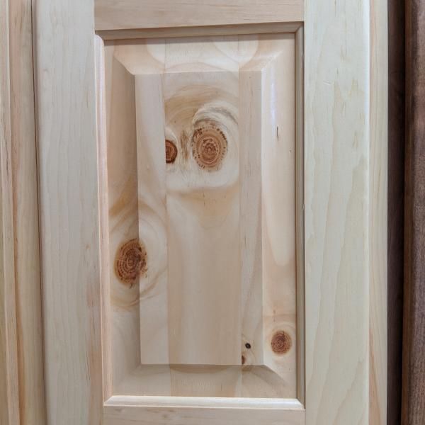 Wooden cabinet door with recessed panel and visible knots in light pine finish