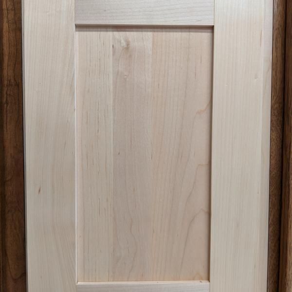 Close-up of a light wood cabinet door with a recessed center panel.