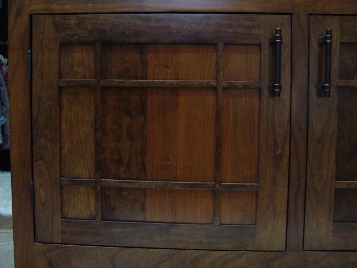 Wooden cabinet doors with dark handles and paneled glass inset on one door