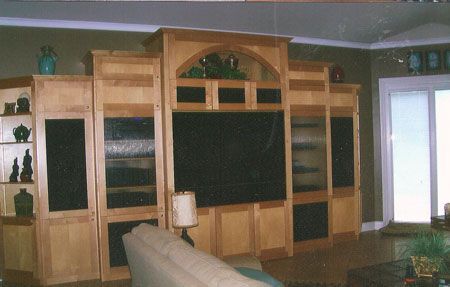 Wood-paneled living room with built-in entertainment center and large TV on a beige wall.