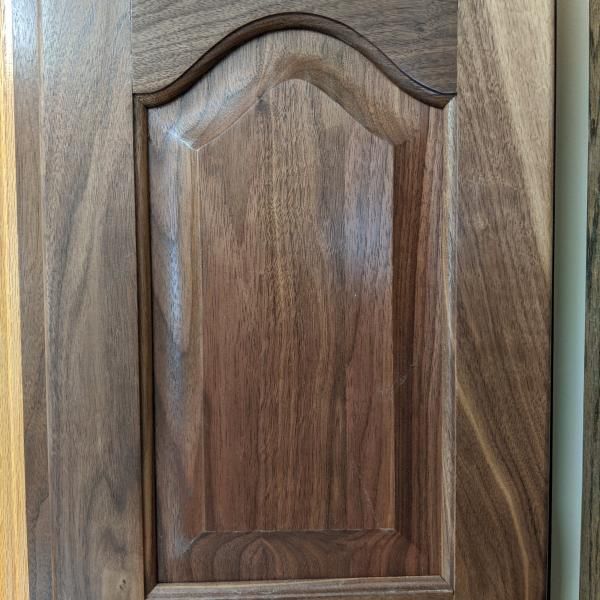 Wooden cabinet door with arched panel and dark stained finish