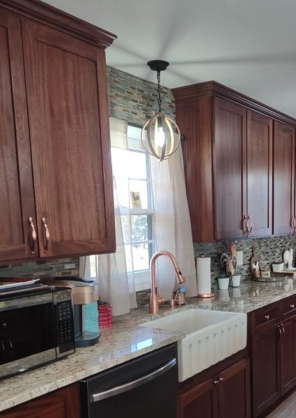 Kitchen with dark wood cabinets, granite countertop, window above sink, and pendant light.