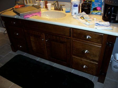 Bathroom vanity with dark wood cabinets, beige countertop, sink, and toiletries on top.