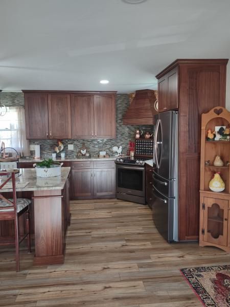 Modern kitchen with wood cabinets, black appliances, tile backsplash, and wood-look flooring