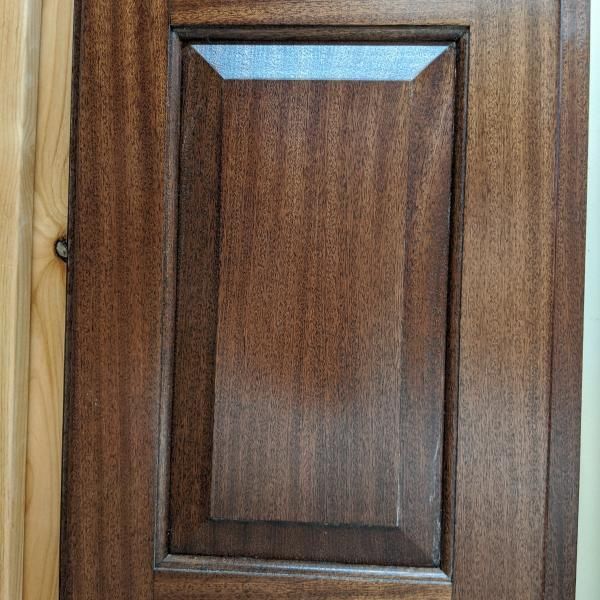 Wooden cabinet door with a recessed rectangular panel and dark brown wood grain finish
