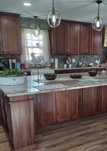 Bright kitchen with dark wood cabinets, granite island, pendant lights, and a window over the sink