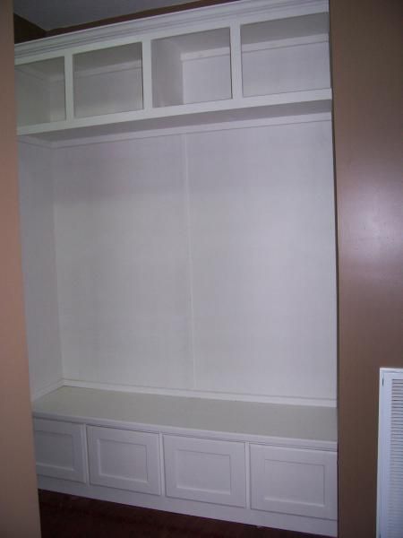 Empty white built-in closet with upper shelves and lower cabinets in a bedroom.