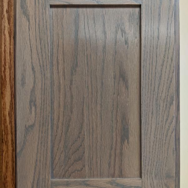 Close-up of a brown wood cabinet door with a recessed rectangular panel.