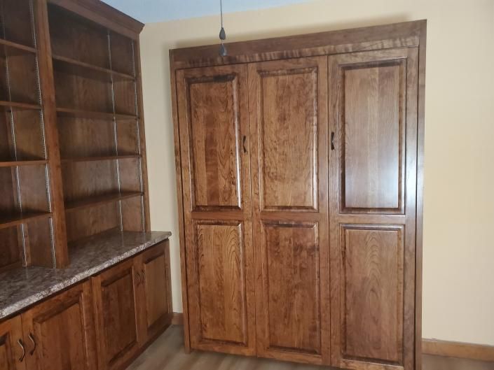 Wooden built-in shelves, cabinets, and double closet doors in a beige room.