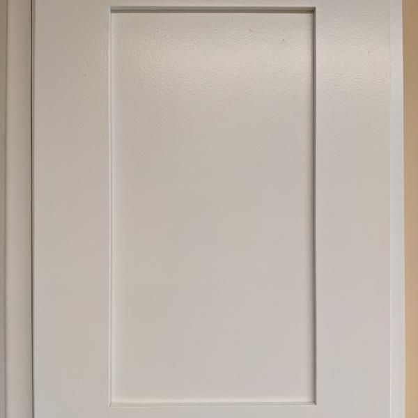 White recessed panel cabinet or closet door against a light-colored wall.