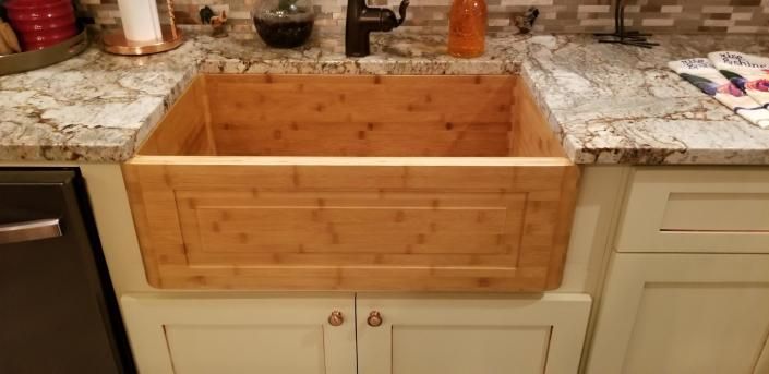Wooden cabinet drawer open under a kitchen countertop, showing a built-in storage box.