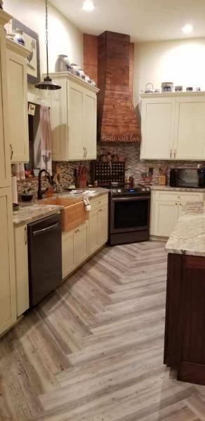 Compact kitchen with cream cabinets, dark countertops, brick backsplash, and stainless appliances.