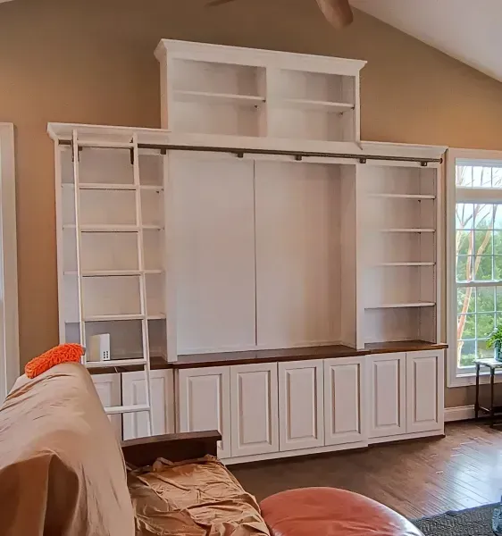 Built-in white wall unit with shelves and cabinets in a living room, ready for a TV or display.