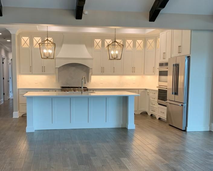 Bright white modern kitchen with large island, stainless steel appliances, and hardwood floors