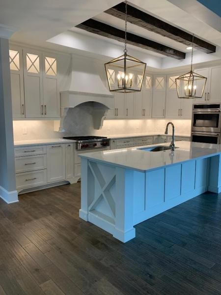 Bright white kitchen with island, pendant lights, and dark wood floors