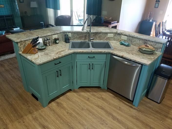 Teal kitchen island with granite countertop, sink, stovetop, and dishwasher in a modern kitchen