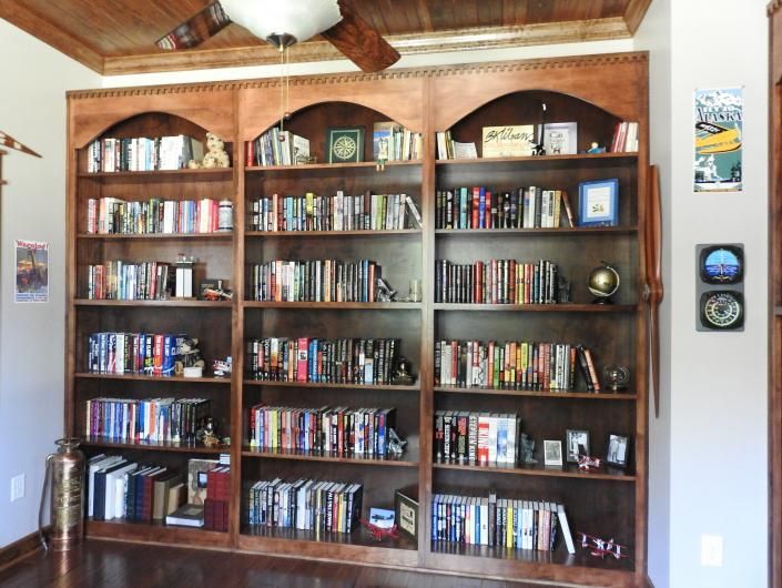 Built-in wooden bookshelf filled with books and decor in a cozy room