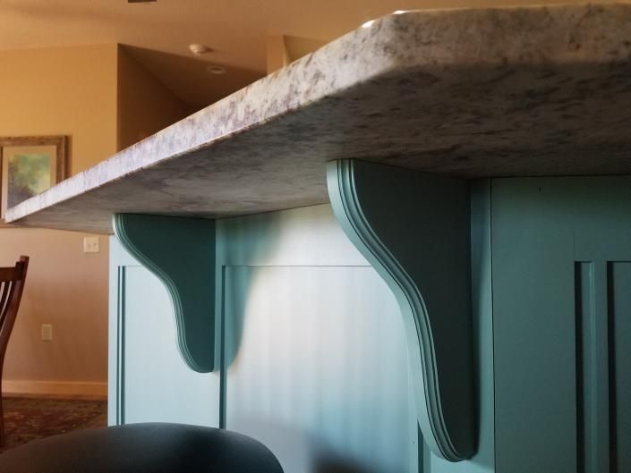 Close-up of a turquoise kitchen island with a speckled granite countertop in a home interior
