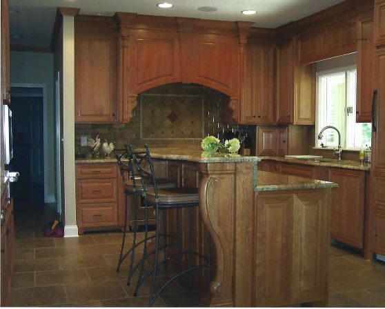 Warm wood kitchen with island, bar stools, granite counters, and a large window by the sink.