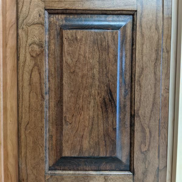 Close-up of a wooden cabinet door with a recessed rectangular panel.