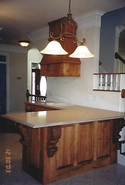 Wooden kitchen island with marble countertop and hanging pendant lights in a home kitchen
