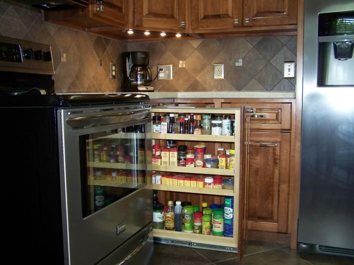 Open pantry built into a kitchen cabinet, stocked with jars, cans, and pantry items.