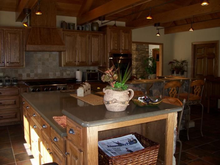 Warm-toned kitchen with wooden cabinets, island, and a plant centerpiece on a counter.