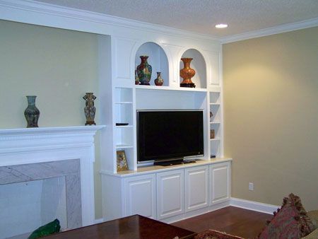 Living room with built-in white entertainment center, TV, fireplace, and decorative shelves