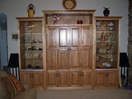 Wooden entertainment center with cabinets and glass shelves in a living room