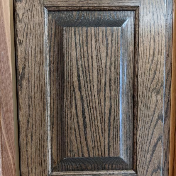 Close-up of a wood-grain cabinet door with a recessed panel