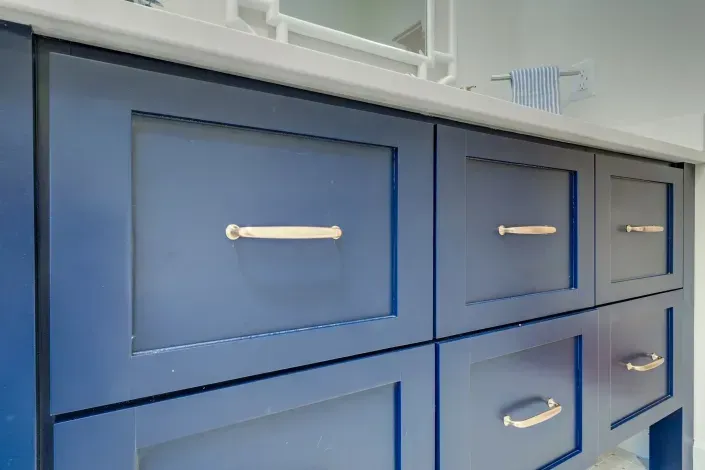 Blue kitchen cabinet with silver handles under a countertop sink