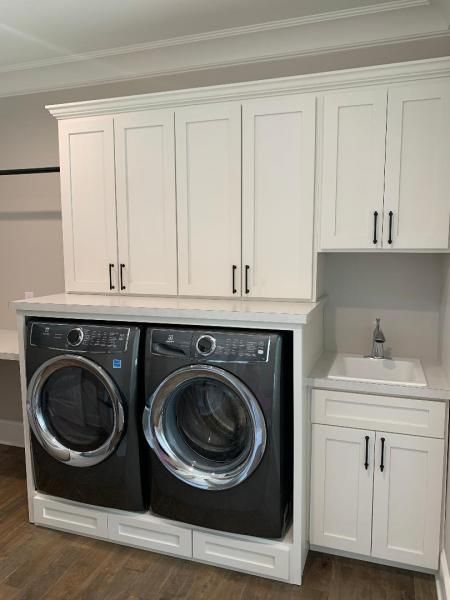 Built-in white cabinets and countertop laundry area with black front-load washer and dryer.