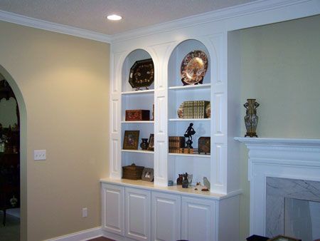 Built-in white shelving with decor in a beige living room beside a fireplace