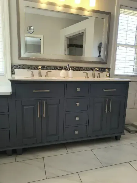 Dark vanity with double sinks and large mirror in a tiled bathroom