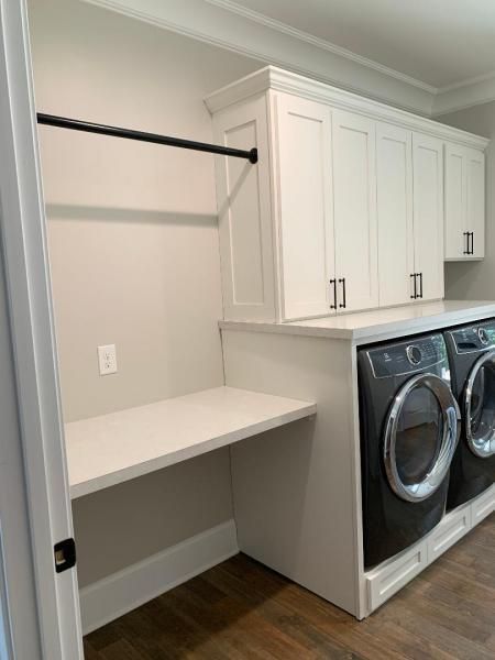 Laundry room with white cabinets, counter, hanging rod, and front-loading washer and dryer