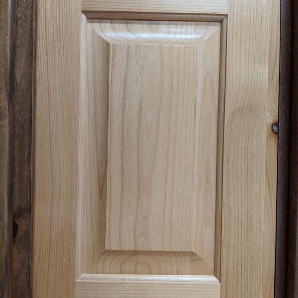 Close-up of a light wood cabinet door with a raised panel design