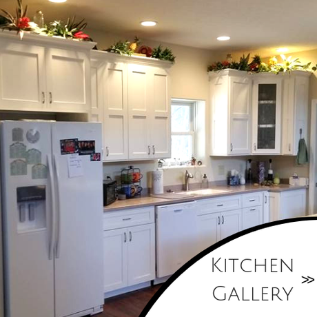 Bright white kitchen with cabinets, refrigerator, and countertop decor, labeled “Kitchen Gallery”