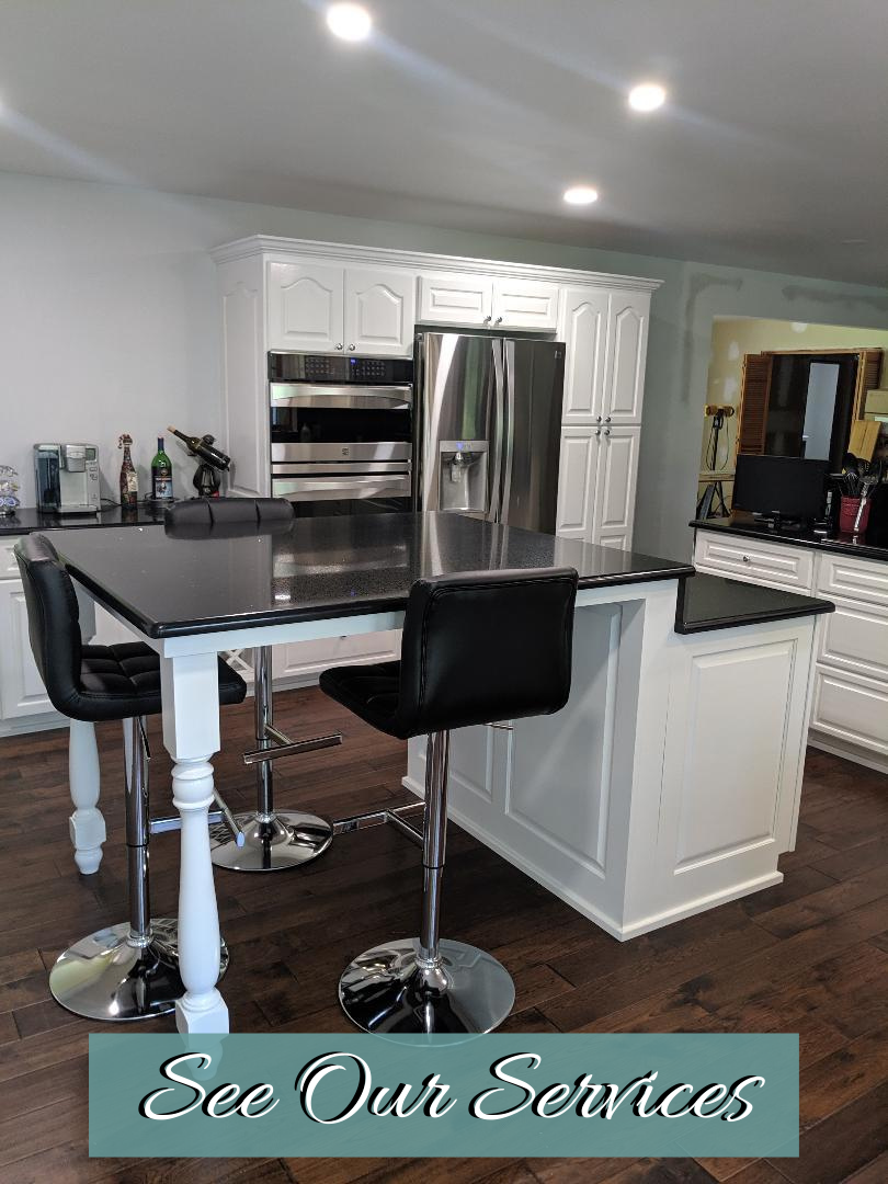 Modern kitchen with white cabinets, stainless appliances, black island counter, and two bar stools.