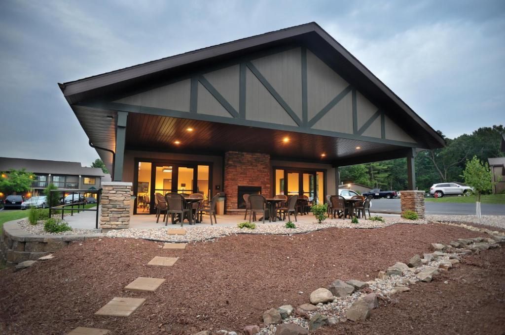 Stone lodge with lit porch and outdoor seating at dusk, set against a cloudy sky