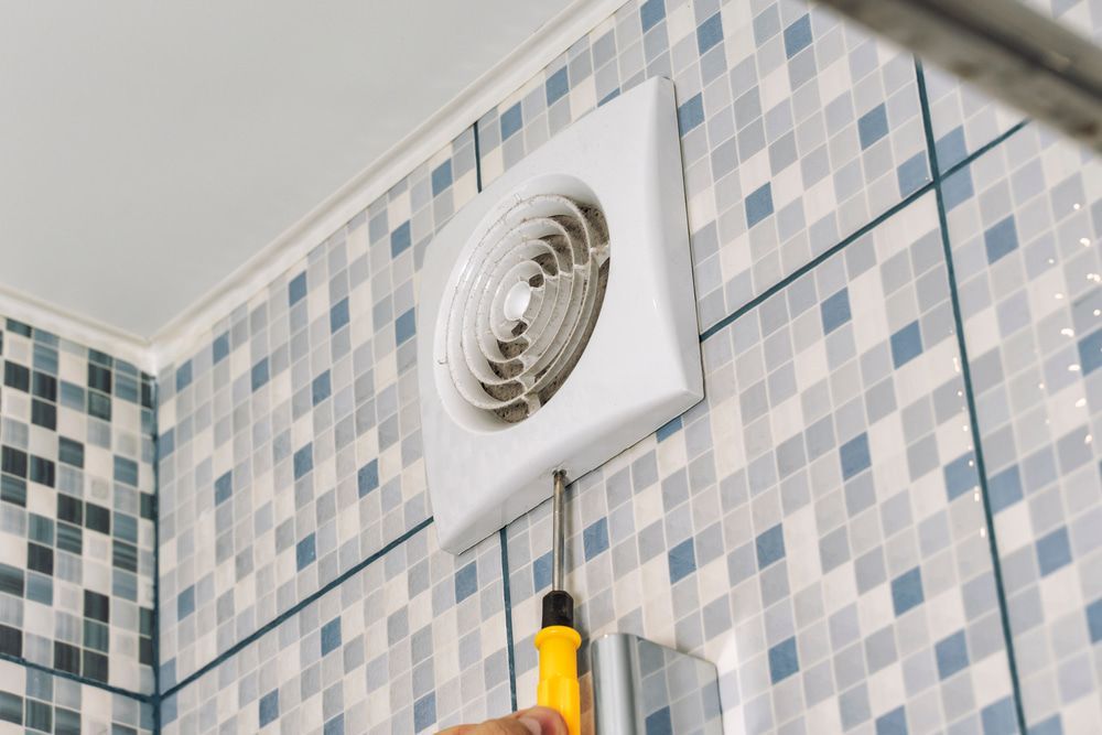 A Person Is Installing A Bathroom Fan On A Tiled Wall — The Woolmen In Alstonville, NSW