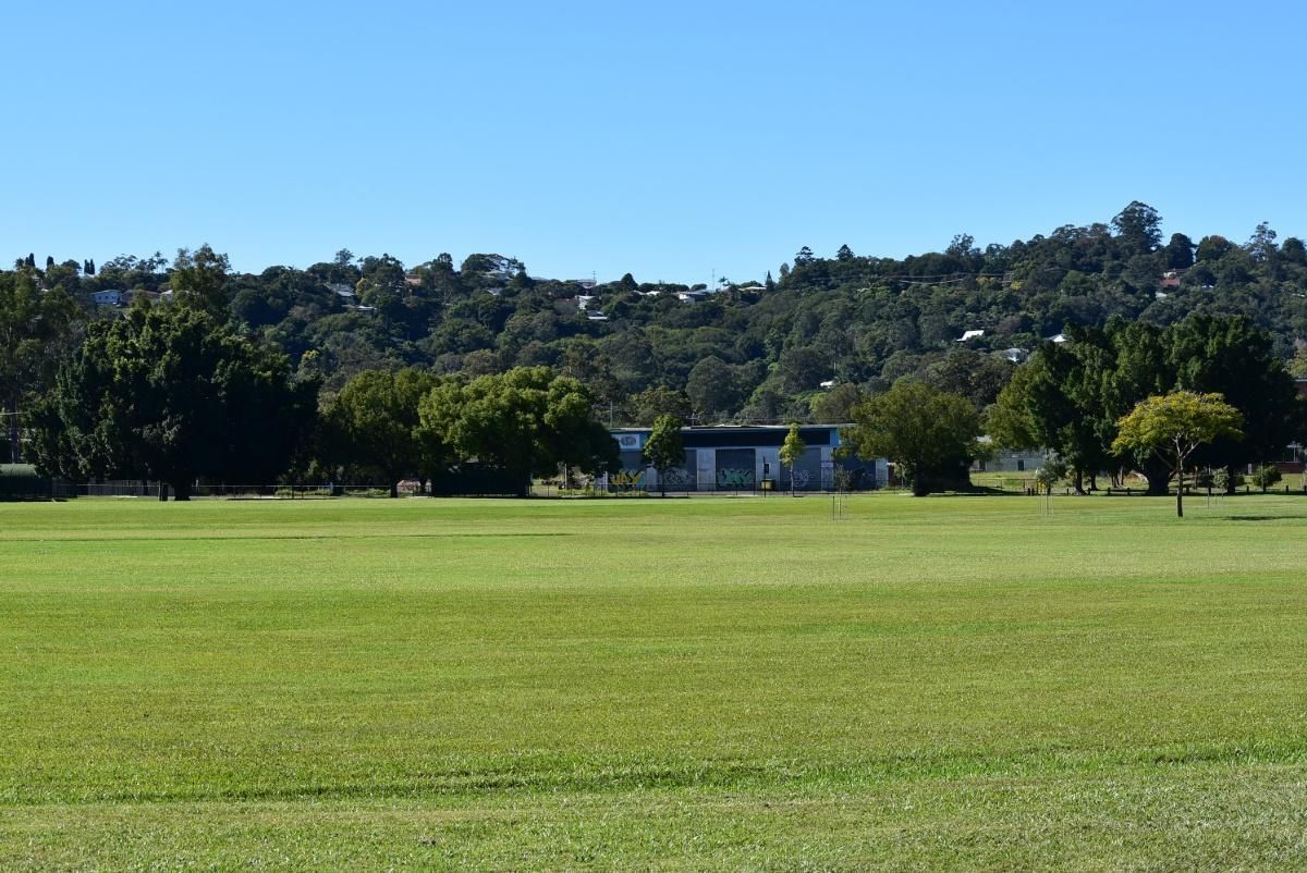 A Large Grassy Field With Trees In The Background — The Woolmen In Lismore, NSW