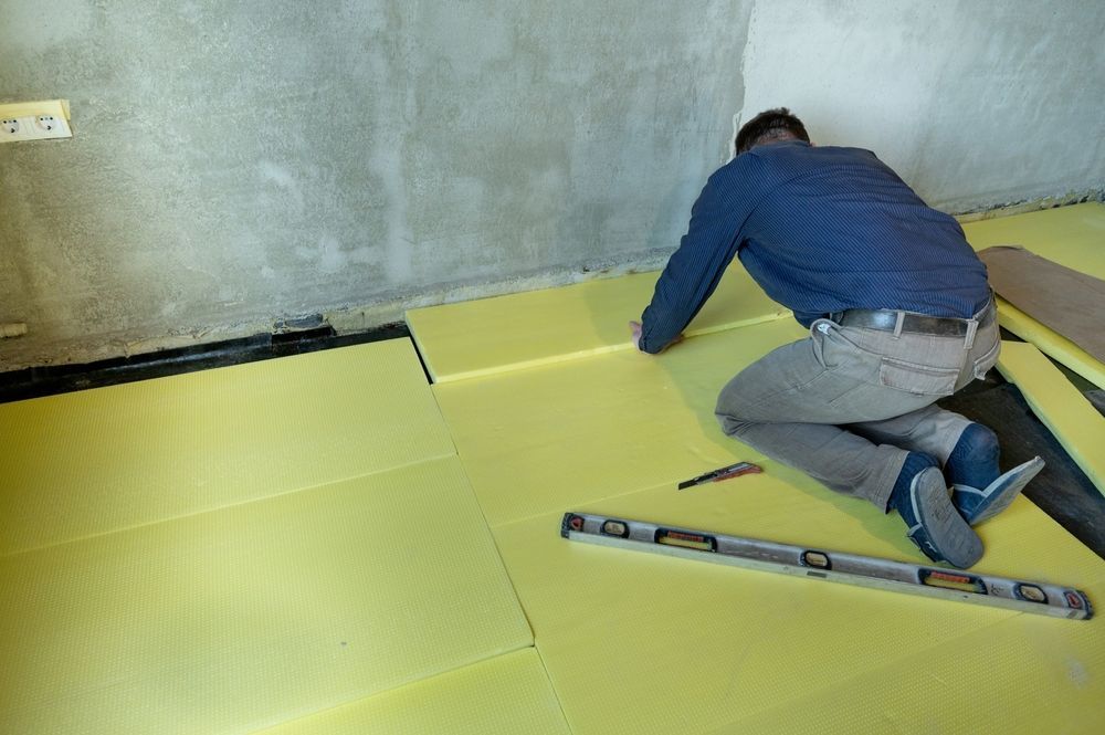 A Man Is Installing Insulation On A Floor In A Room — The Woolmen In Byron Bay, NSW