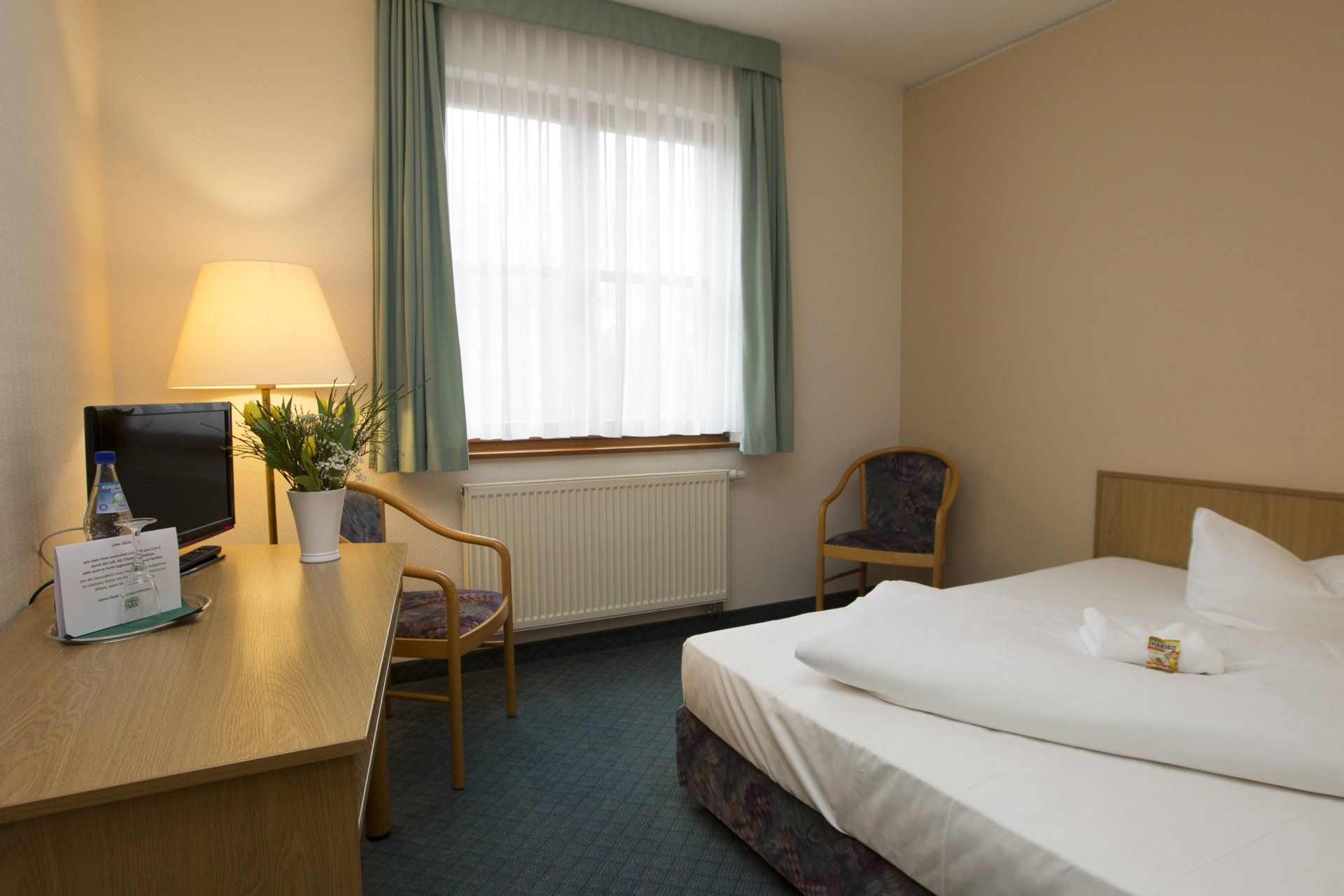 Ein Hotelzimmer mit Bett, Schreibtisch, Stuhl und Fernseher.