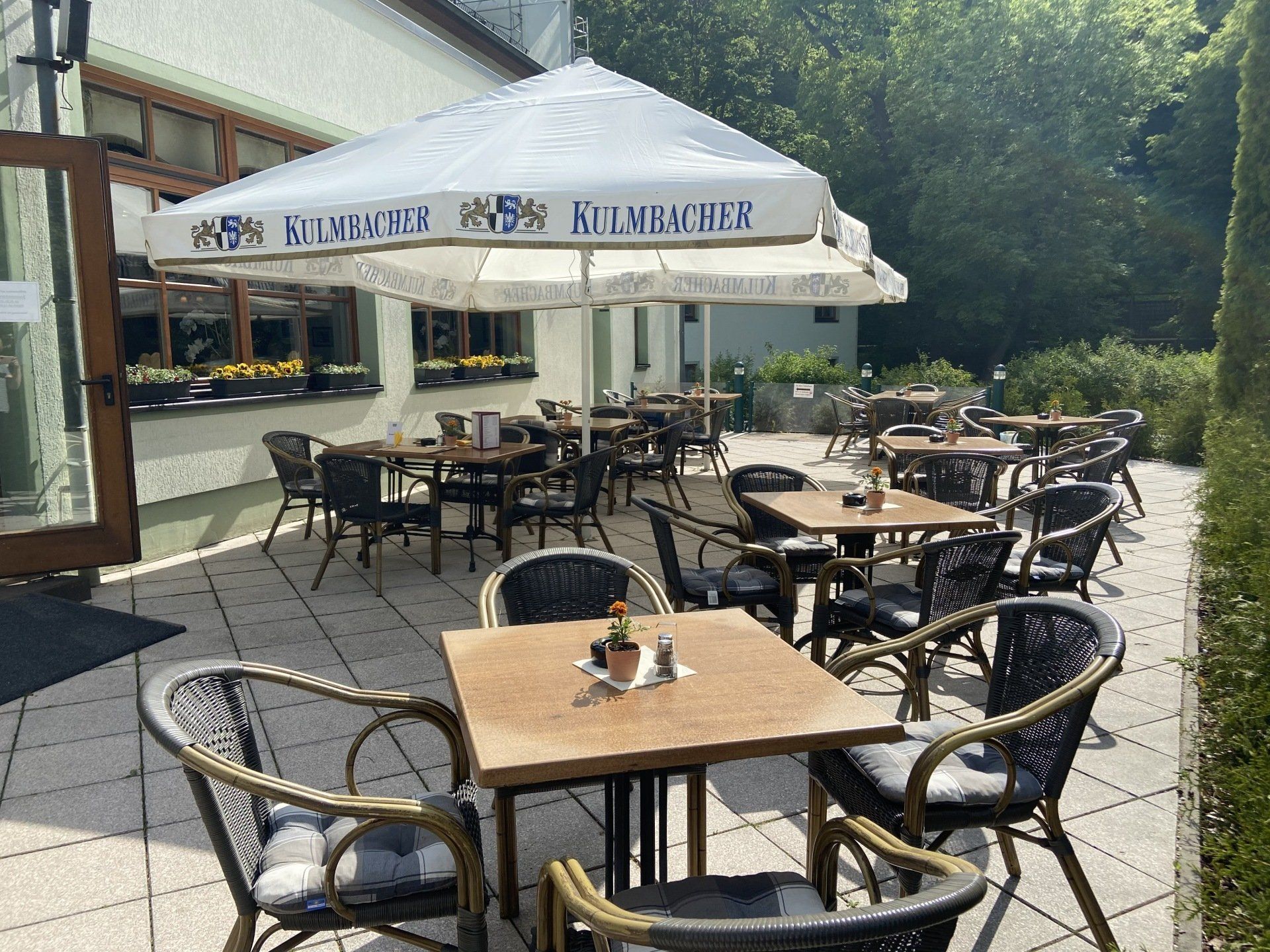 Eine Restaurantterrasse mit Tischen und Stühlen und einem Sonnenschirm.