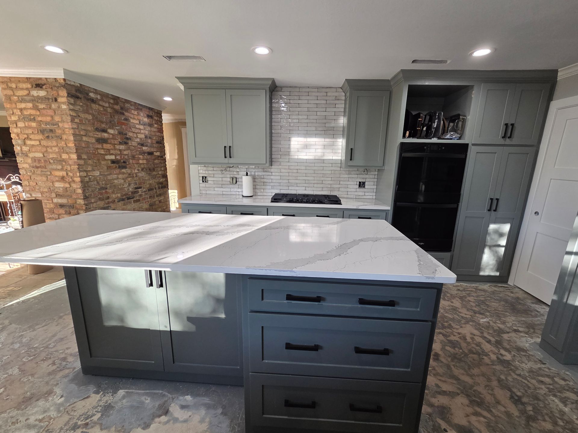 Modern kitchen with gray island, white countertops, and built-in stainless appliances