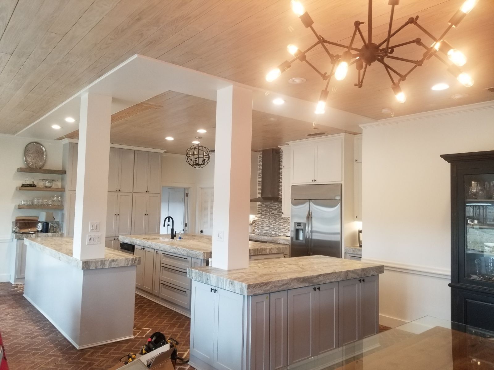 Modern open-plan kitchen with gray cabinets, marble island, stainless appliances, and pendant lighting