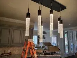 Modern kitchen with hanging pendant lights and an orange ladder underneath